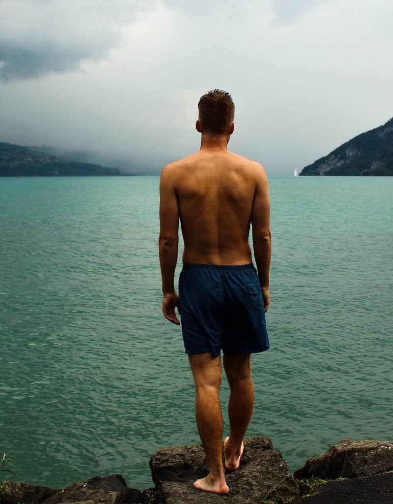 Man standing on rocks staring out at a lake